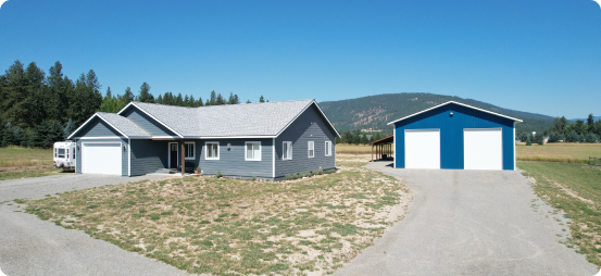 A house with two garage doors in the middle of an empty lot.